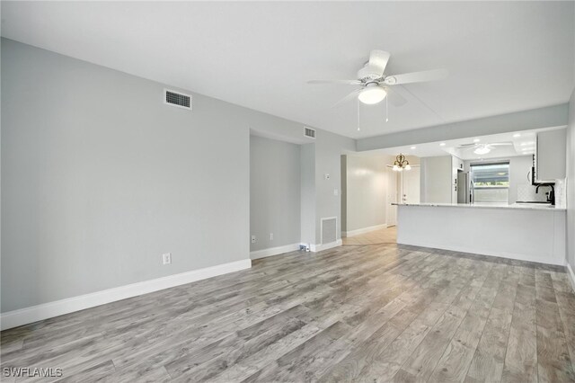 16001 Dublin Cir Unit 103, Fort Myers, FL 33908 - unfurnished living room featuring ceiling fan, light wood-style floors, and a chandelier