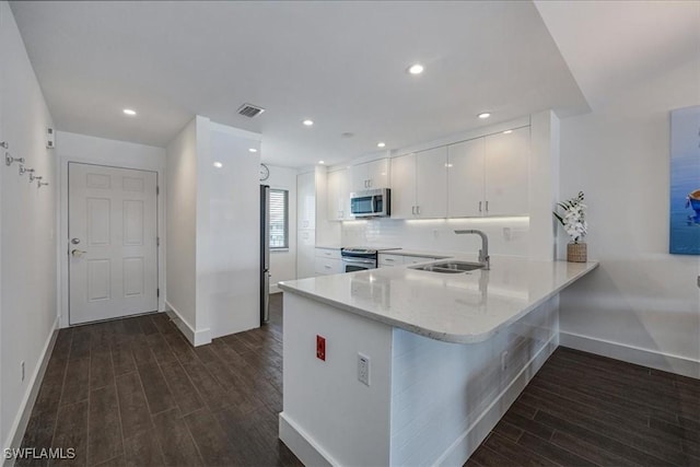 10682 Gulf Shore Dr Unit C302, Naples, FL 34108 - kitchen with appliances with stainless steel finishes, dark wood-style flooring, white cabinetry, a peninsula, and a kitchen breakfast bar