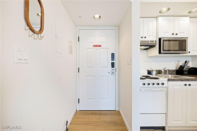 8771 Estero Blvd Unit 607, Fort Myers Beach, FL 33931 - kitchen featuring stainless steel microwave, white range oven, white cabinetry, light wood-style floors, and dark countertops