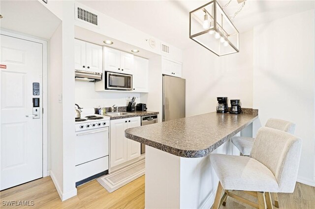8771 Estero Blvd Unit 607, Fort Myers Beach, FL 33931 - kitchen featuring appliances with stainless steel finishes, under cabinet range hood, a peninsula, dark countertops, and a kitchen bar