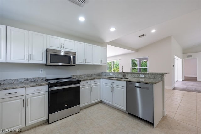 2790 Randall Blvd, Naples, FL 34120 - kitchen featuring appliances with stainless steel finishes, a peninsula, white cabinets, vaulted ceiling, and light stone countertops