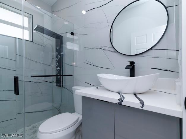 3103 13th St SW, Lehigh Acres, FL 33976 - bathroom with vanity, a marble finish shower, and tile walls