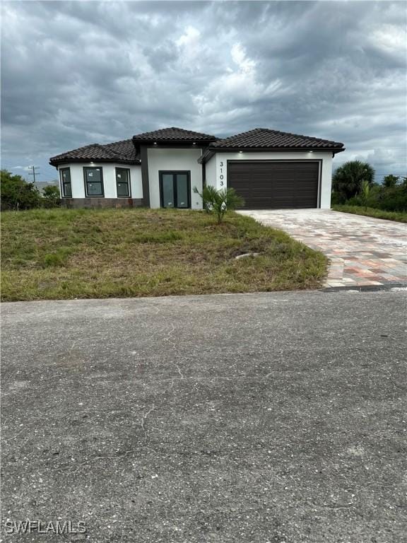 3103 13th St SW, Lehigh Acres, FL 33976 - view of front of property featuring an attached garage, driveway, stucco siding, and a tile roof