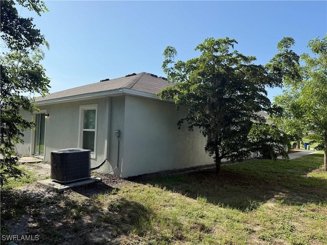 9069 Aegean Cir, Lehigh Acres, FL 33936 - view of side of home featuring a central AC unit and stucco siding
