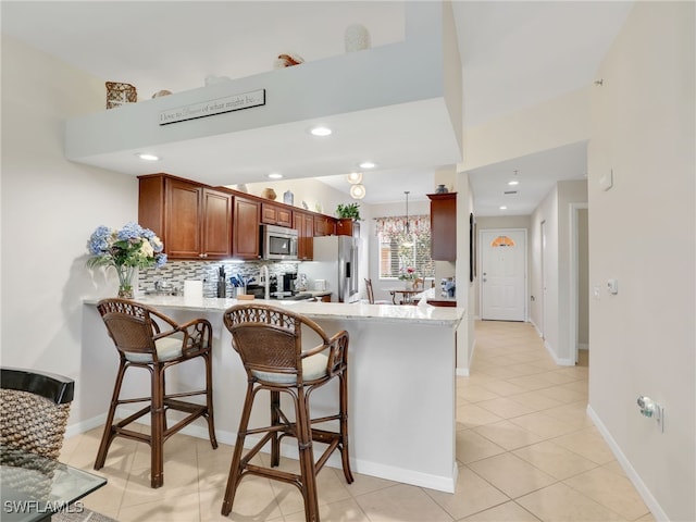 6790 Beach Resort Dr Unit 13, Naples, FL 34114 - kitchen with appliances with stainless steel finishes, a peninsula, light countertops, tasteful backsplash, and a breakfast bar area
