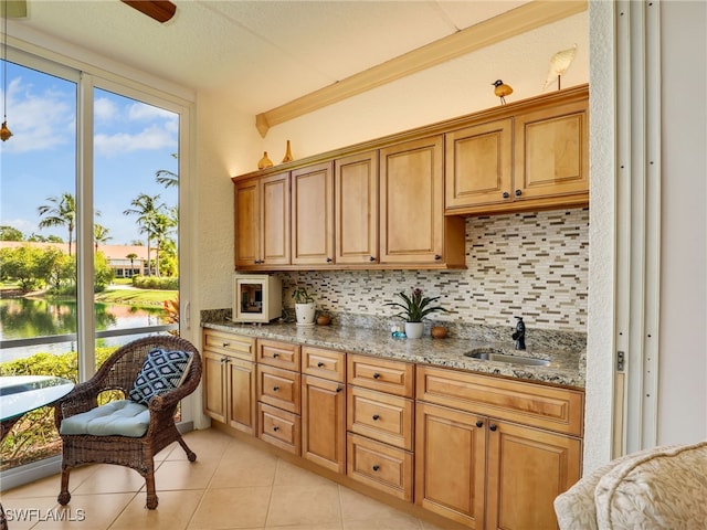 6790 Beach Resort Dr Unit 13, Naples, FL 34114 - kitchen featuring tasteful backsplash, light stone countertops, a water view, light tile patterned floors, and brown cabinets