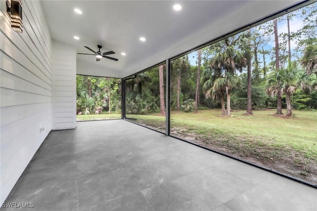 431 1st St NW, Naples, FL 34120 - unfurnished sunroom featuring a ceiling fan and view of wooded area