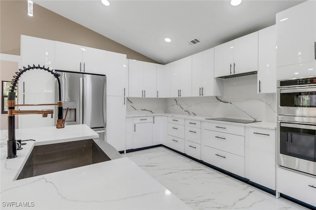 431 1st St NW, Naples, FL 34120 - kitchen with stainless steel appliances, light marble finish flooring, white cabinets, recessed lighting, and vaulted ceiling