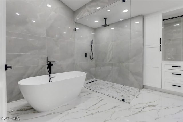 431 1st St NW, Naples, FL 34120 - bathroom featuring tile walls, marble tiled flooring, a soaking tub, and walk in shower