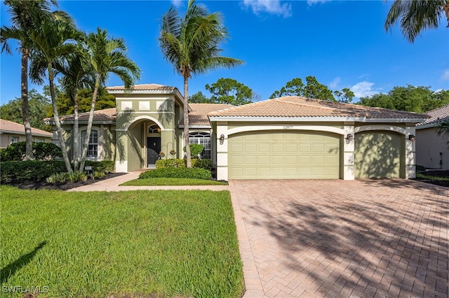 12977 Turtle Cove Trl, North Fort Myers, FL 33903 - mediterranean / spanish home featuring stucco siding, an attached garage, a tile roof, decorative driveway, and a front lawn