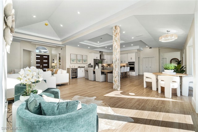 5203 Starfish Ave, Naples, FL 34103 - living room with vaulted ceiling, beverage cooler, a fireplace, light wood finished floors, and a tray ceiling