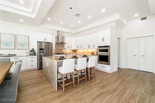 5203 Starfish Ave, Naples, FL 34103 - kitchen with stainless steel appliances, wall chimney exhaust hood, a kitchen breakfast bar, decorative backsplash, and a kitchen island with sink