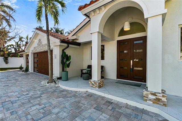 5203 Starfish Ave, Naples, FL 34103 - doorway to property with french doors, stucco siding, a garage, and a tile roof