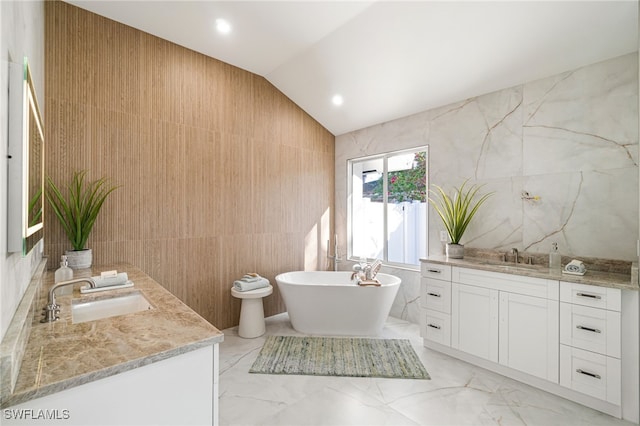 5203 Starfish Ave, Naples, FL 34103 - bathroom with tile walls, double vanity, a freestanding bath, lofted ceiling, and marble tiled flooring
