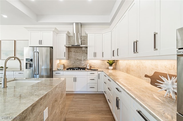 5203 Starfish Ave, Naples, FL 34103 - kitchen featuring high end refrigerator, wall chimney range hood, gas stovetop, light stone countertops, and white cabinetry