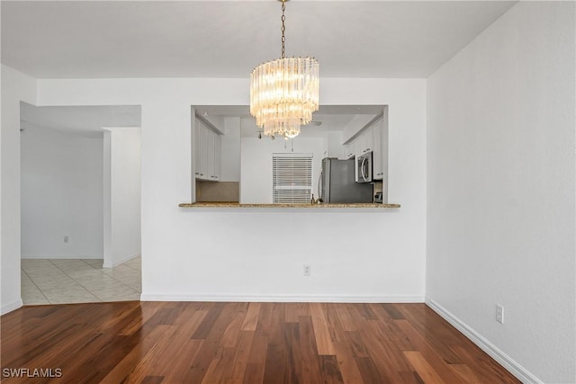 9650 Victoria Ln Unit 201B, Naples, FL 34109 - kitchen with stainless steel appliances, a chandelier, wood finished floors, and white cabinetry