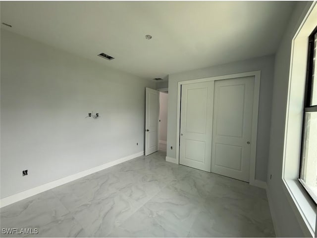 3722 29th Ave NE, Naples, FL 34120 - unfurnished bedroom featuring light marble finish flooring and a closet