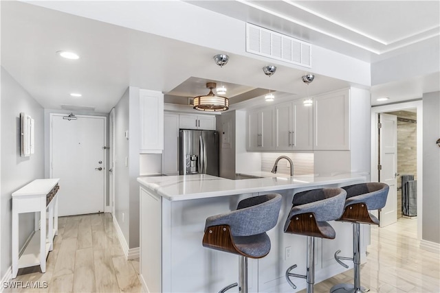 180 Seaview Ct Unit 507, Marco Island, FL 34145 - kitchen with stainless steel fridge with ice dispenser, light countertops, a peninsula, a kitchen bar, and a raised ceiling