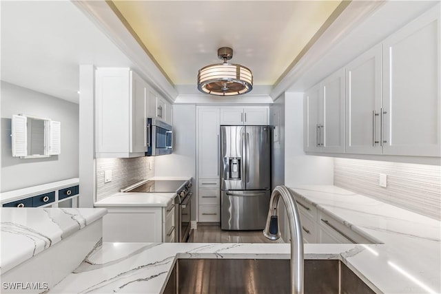 180 Seaview Ct Unit 507, Marco Island, FL 34145 - kitchen featuring stainless steel appliances, white cabinets, decorative backsplash, and light stone counters