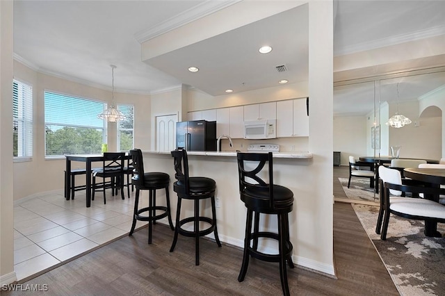 8610 Cedar Hammock Cir Unit 1223, Naples, FL 34112 - kitchen with white microwave, freestanding refrigerator, a chandelier, light countertops, and ornamental molding