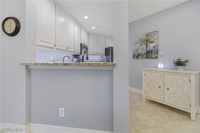 6770 Huntington Lakes Cir Unit 203, Naples, FL 34119 - kitchen with freestanding refrigerator, white cabinets, light stone counters, recessed lighting, and a peninsula