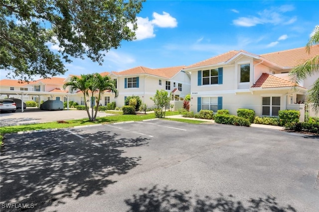 5040 Cedar Springs Dr Unit 201, Naples, FL 34110 - view of front facade featuring uncovered parking, a tiled roof, and stucco siding