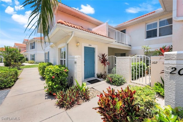 5040 Cedar Springs Dr Unit 201, Naples, FL 34110 - entrance to property with stucco siding, a gate, a balcony, and a tile roof