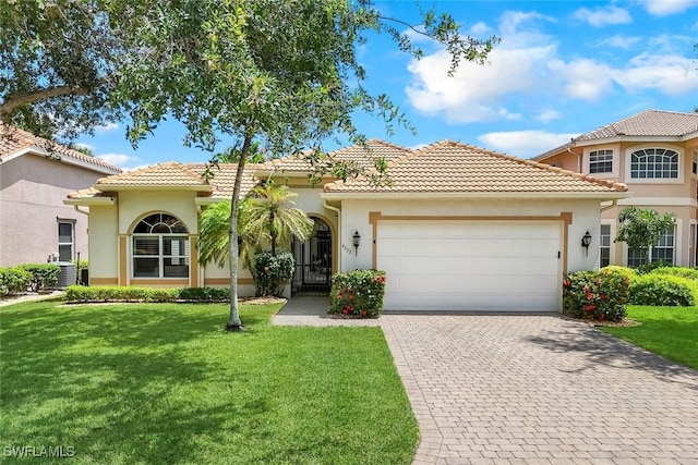 4333 Mistlethrush Ln, Naples, FL 34119 - mediterranean / spanish-style home featuring an attached garage, decorative driveway, a front lawn, and stucco siding