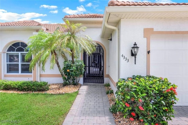 4333 Mistlethrush Ln, Naples, FL 34119 - view of exterior entry featuring an attached garage, stucco siding, and a tile roof