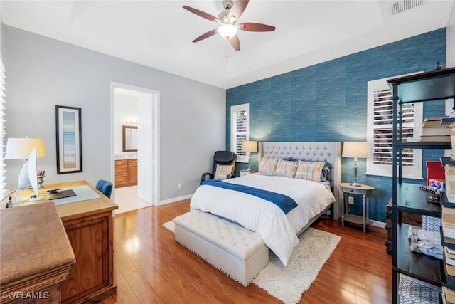 4333 Mistlethrush Ln, Naples, FL 34119 - bedroom with a desk, wood finished floors, wallpapered walls, ceiling fan, and ensuite bath