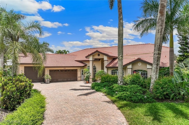 11840 Longshore Way W, Naples, FL 34119 - mediterranean / spanish house with stucco siding, a tiled roof, an attached garage, and decorative driveway