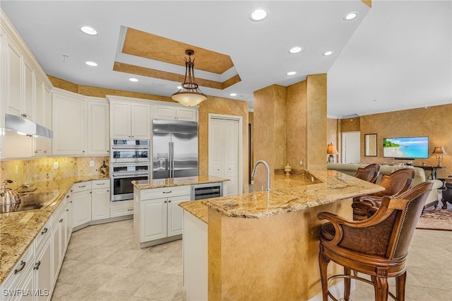 4137 Bay Beach Ln Unit 5P2, Fort Myers Beach, FL 33931 - kitchen with a peninsula, light stone countertops, stainless steel appliances, a kitchen bar, and decorative backsplash