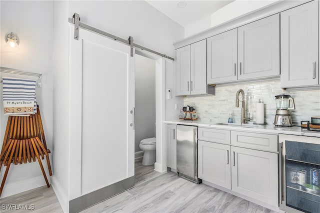 4137 Bay Beach Ln Unit 5P2, Fort Myers Beach, FL 33931 - kitchen with a barn door, light countertops, backsplash, and light wood-type flooring