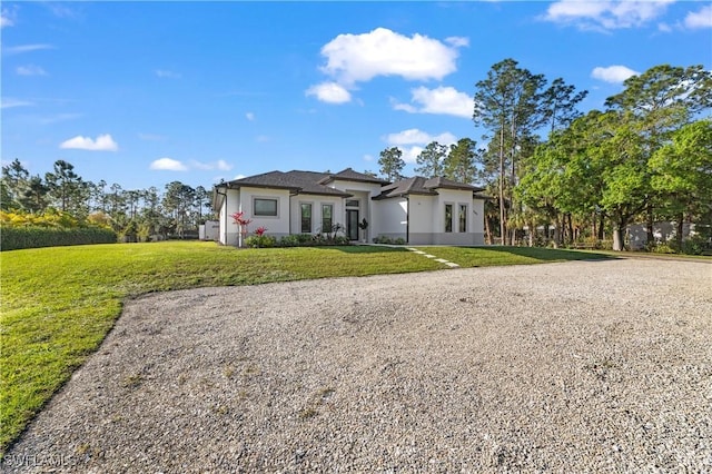 2642 10th Ave NE, Naples, FL 34120 - prairie-style home featuring a front lawn, stucco siding, and gravel driveway