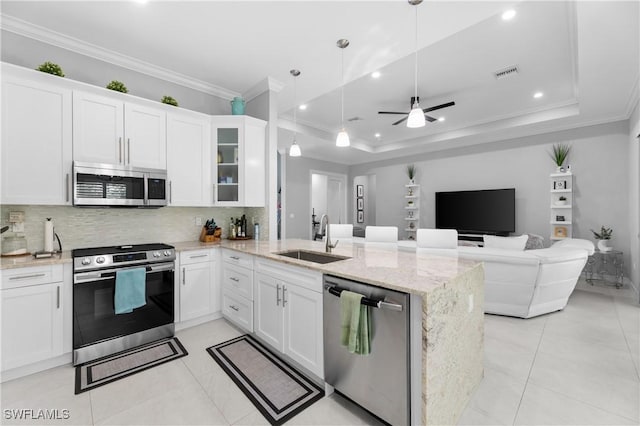 2642 10th Ave NE, Naples, FL 34120 - kitchen with stainless steel appliances, ornamental molding, a peninsula, decorative backsplash, and white cabinetry