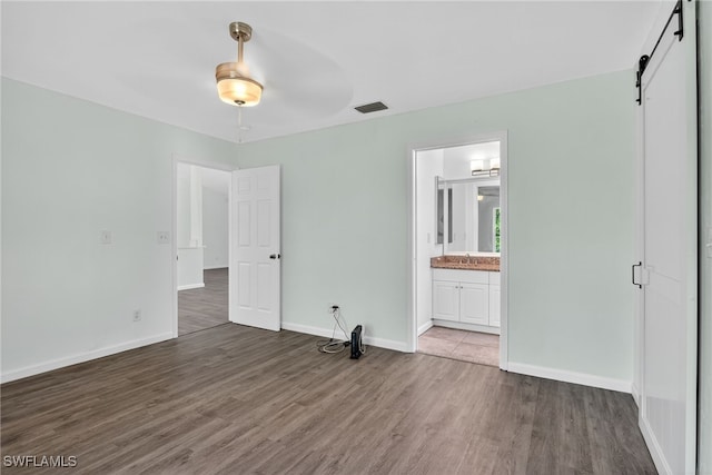 1905 SW 11th St, Cape Coral, FL 33991 - unfurnished bedroom with wood finished floors, a barn door, and ensuite bath