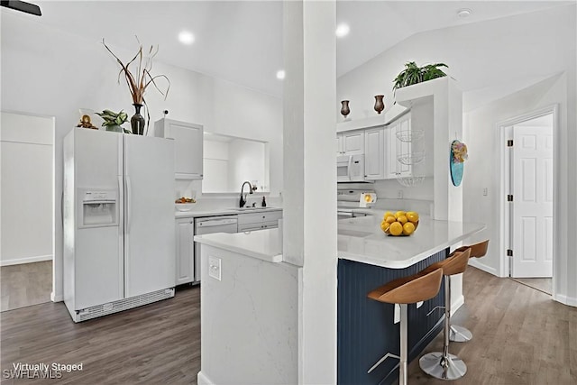 1905 SW 11th St, Cape Coral, FL 33991 - kitchen with white appliances, white cabinetry, wood finished floors, a kitchen bar, and lofted ceiling