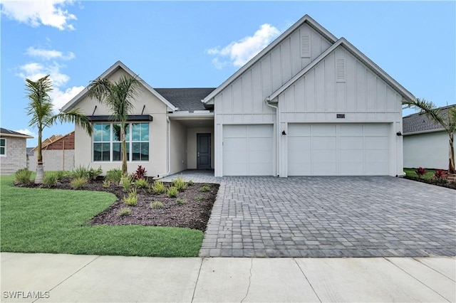 16272 Wax Myrtle St, Punta Gorda, FL 33982 - view of front of home featuring board and batten siding, decorative driveway, a garage, and a front yard