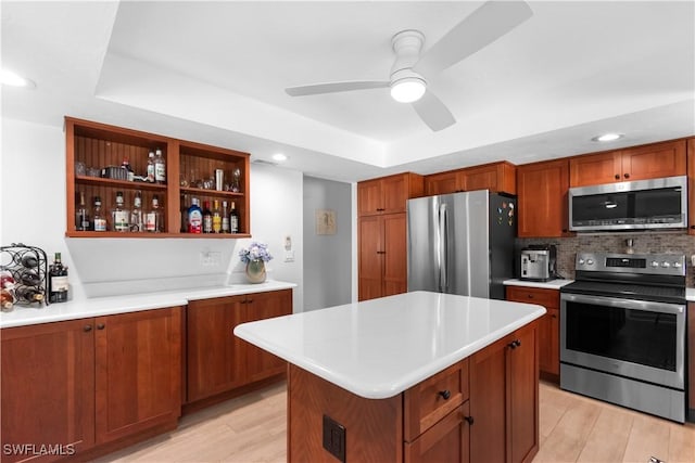 18381 Panther Trail Ln, North Fort Myers, FL 33917 - kitchen featuring stainless steel appliances, a tray ceiling, light countertops, brown cabinetry, and light wood-style floors