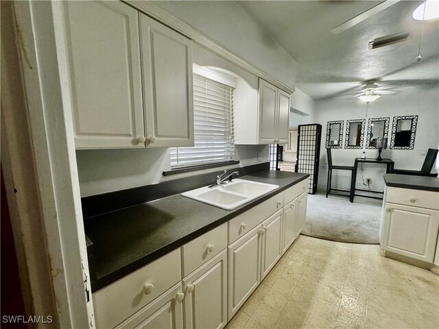 1427 Charles Rd, Fort Myers, FL 33919 - kitchen featuring a ceiling fan, dark countertops, light colored carpet, and white cabinetry