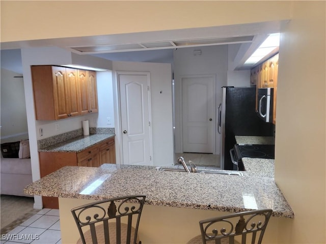 4619 SW 20th Pl, Cape Coral, FL 33914 - kitchen featuring stainless steel microwave, a kitchen breakfast bar, electric range oven, brown cabinets, and a peninsula