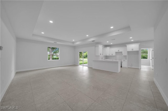933 Anthony St E, Lehigh Acres, FL 33974 - unfurnished living room featuring a raised ceiling, plenty of natural light, recessed lighting, and light tile patterned floors