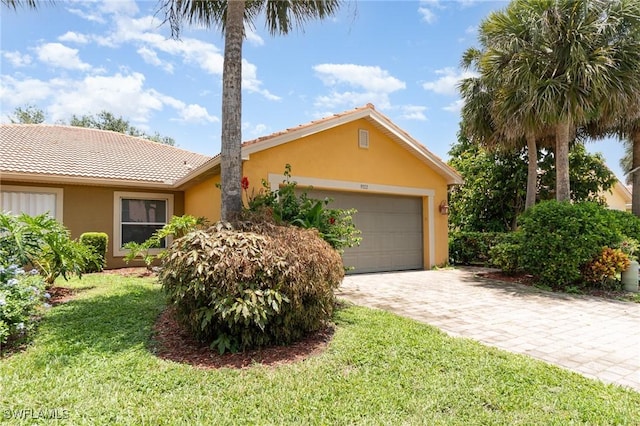 9322 Aegean Cir, Lehigh Acres, FL 33936 - ranch-style home featuring stucco siding, a front yard, a garage, and a tile roof