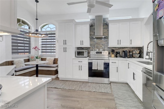 8644 Ibis Cove Cir, Naples, FL 34119 - kitchen with electric range, wall chimney range hood, light countertops, and backsplash