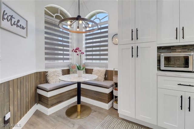 8644 Ibis Cove Cir, Naples, FL 34119 - dining space featuring breakfast area, a chandelier, a wainscoted wall, wooden walls, and light wood finished floors