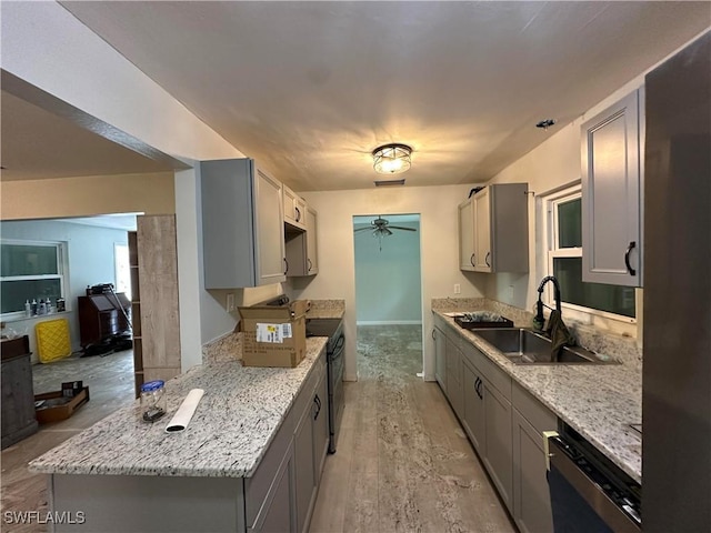 16940 Tarpon Way N, Fort Myers, FL 33917 - kitchen featuring gray cabinets, a ceiling fan, dishwashing machine, light stone counters, and light wood-type flooring