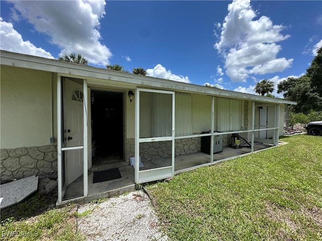 16940 Tarpon Way N, Fort Myers, FL 33917 - back of property featuring a sunroom, a yard, and stucco siding