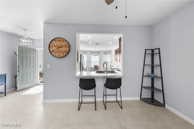 2245 Pigeon Plum Way N, Fort Myers, FL 33917 - kitchen featuring stainless steel fridge with ice dispenser, a kitchen bar, light tile patterned floors, light countertops, and a peninsula
