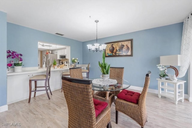 20013 Petrucka Cir N, Lehigh Acres, FL 33936 - dining area with light wood finished floors and a chandelier