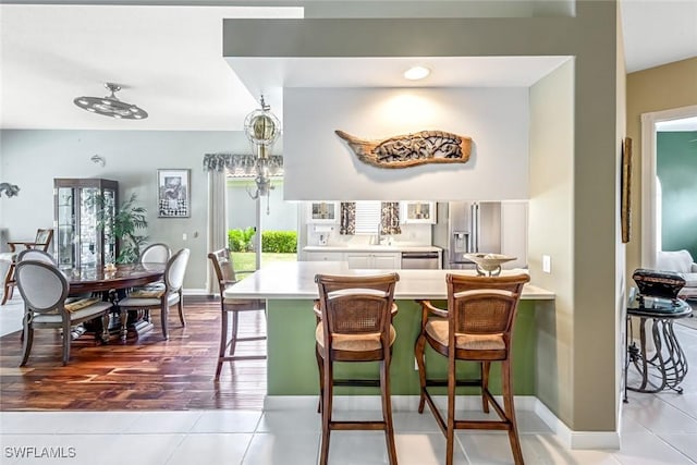 2799 Jude Island Way, Naples, FL 34119 - kitchen with stainless steel appliances, light countertops, a kitchen bar, and tile patterned floors
